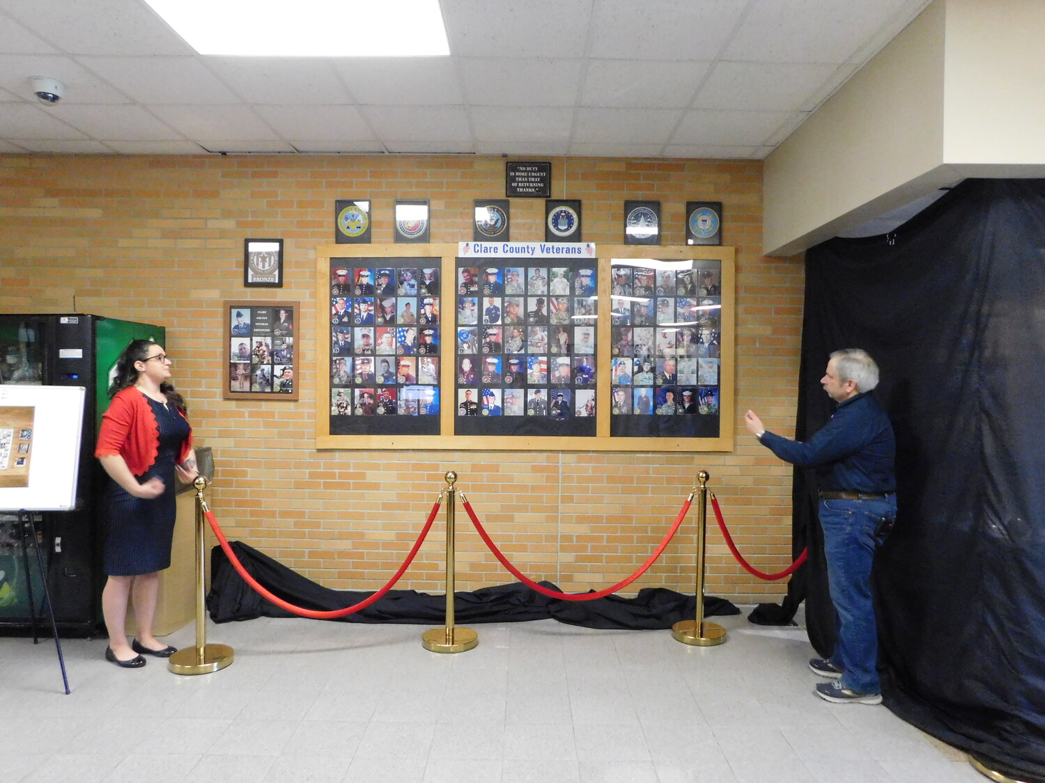 Karl Hauser drops the veiling backdrop curtain Tuesday, May 9, revealing the revamped Honor Wall in the main lobby of the Clare County Building.